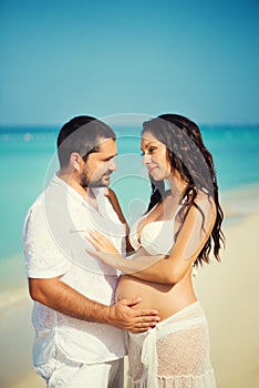 Happy young man and pregnant woman on the sea coast