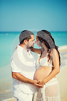 Happy young man and pregnant woman on the sea coast.