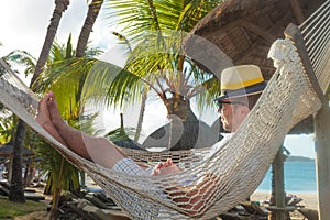 Happy young man resting in a hammock on the beach
