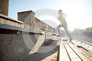 Happy young man running upstairs on stadium