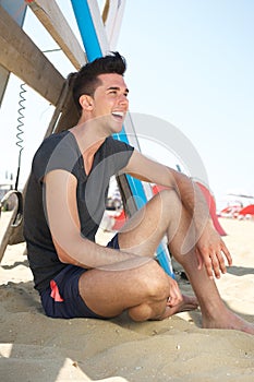 Happy young man sitting at the beach
