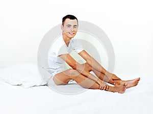 Happy young man sitting on the bed