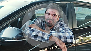 Happy young man sitting in the car, looking out the window. Slow motion