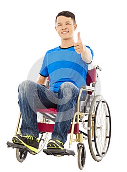 Happy young man sitting on a wheelchair and thumb up