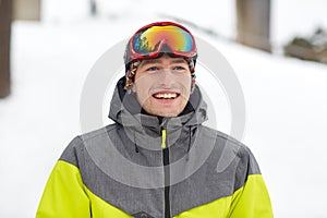 Happy young man in ski goggles outdoors