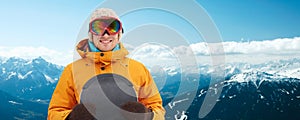 Happy young man in ski goggles over mountains