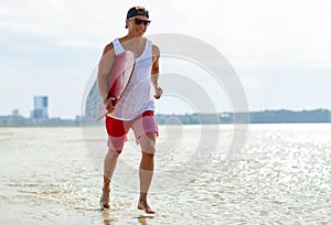 Happy young man with skimboard on summer beach