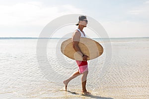 Happy young man with skimboard on summer beach