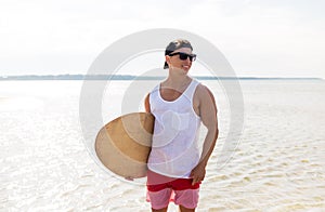 Happy young man with skimboard on summer beach