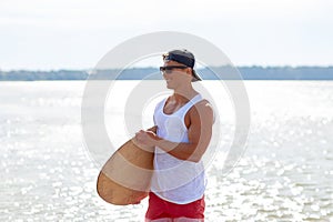 Happy young man with skimboard on summer beach