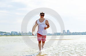 Happy young man with skimboard on summer beach