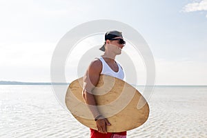 Happy young man with skimboard on summer beach