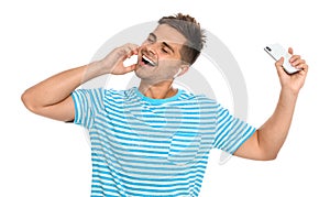 Happy young man with smartphone listening to  through wireless earphones on white background