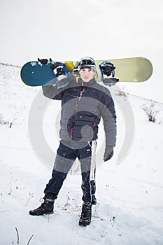 Happy young man with snowboard enjoying sunny weather in snowy mountains. Winter sport and recreation, leasure outdoor activities