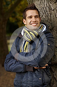 Happy young man standing by tree in park