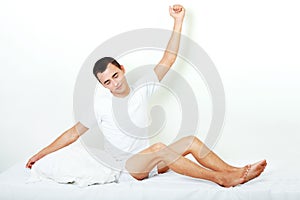 Happy young man stretching on the bed