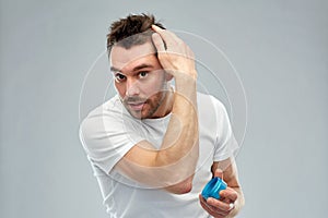 Happy young man styling his hair with wax or gel