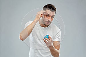 Happy young man styling his hair with wax or gel