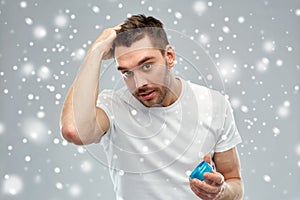 Happy young man styling his hair with wax or gel