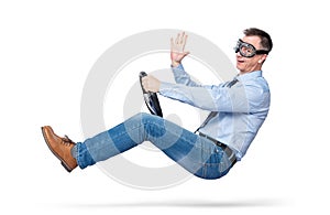 Happy young man in stylish goggles driving a car sends greetings to the camera, isolated on white background. Auto driver concept