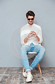 Happy young man in sunglasses listening to music from smartphone