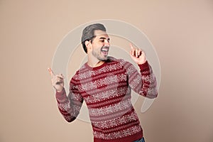 Happy young man in  sweater on beige background