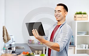 Happy young man with tablet computer in kitchen