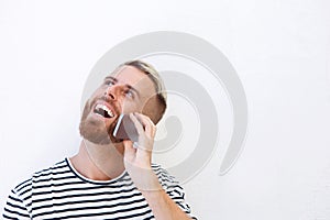 Happy young man talking on cell phone against white background