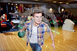 Happy young man throwing ball in bowling club
