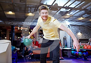 Happy young man throwing ball in bowling club