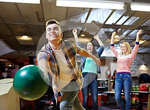 Happy young man throwing ball in bowling club