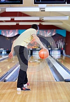 Happy young man throwing ball in bowling club