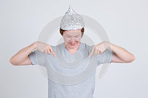 Happy young man with tin foil hat pointing and looking at shirt