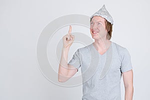 Happy young man with tinfoil hat as conspiracy theory concept pointing up