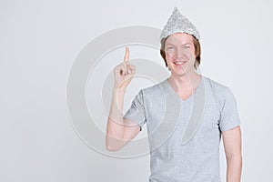 Happy young man with tinfoil hat as conspiracy theory concept pointing up