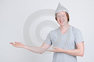 Happy young man with tinfoil hat as conspiracy theory concept showing something