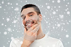 Happy young man touching his face or beard