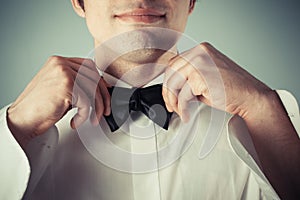 Happy young man tying a bow tie