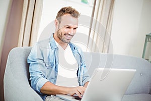 Happy young man using laptop at home