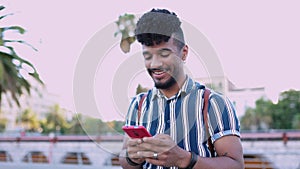 Happy young man using touch mobile phone outdoor on city street