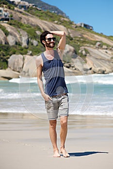 Happy young man on vacation walking barefoot on beach