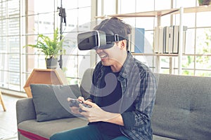 Happy young man with virtual reality headset or 3d glasses with controller gamepad playing video game at home