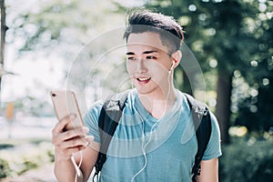 Happy young man  walking on street and using mobile phone