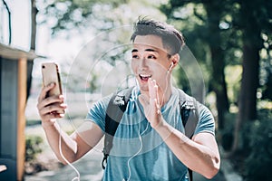 Happy young man  walking on street and using mobile phone