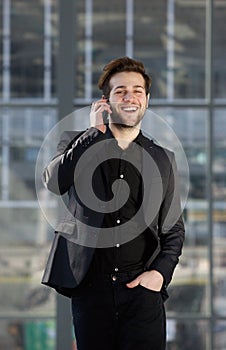 Happy young man walking and talking on mobile phone