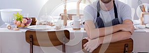 Happy young man wearing apron preparing to cook in kitchen at home, chef with culinary