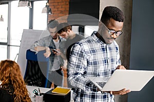 Happy young man wearing glasses working on his laptop