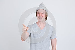 Happy young man wearing tin foil hat as conspiracy theory concept pointing finger