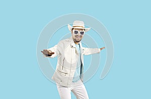 Happy young man in white leather jacket, cowboy hat and sunglasses dancing in studio