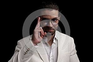 happy young man in white suit smiling and arranging glasses